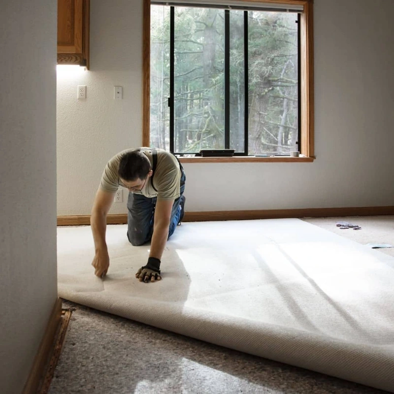 Professional laying out a large white carpet roll in a room