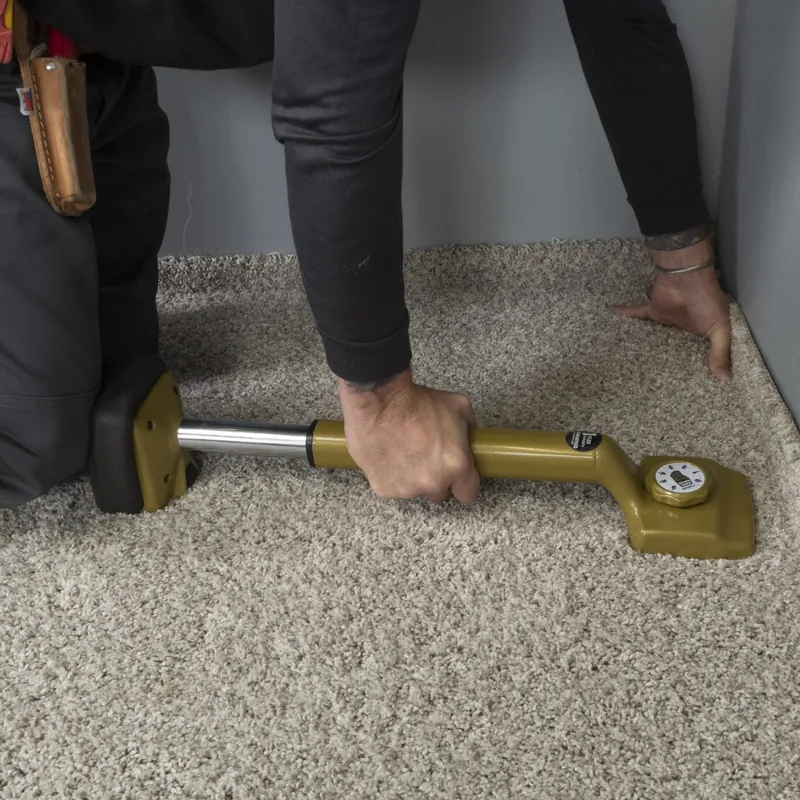 Professional using a gold knee kicker on plush carpet
