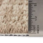 Ruler measuring the pile height of a grey carpet
