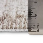 Ruler measuring the pile thickness of grey carpet.