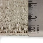 Ruler measuring the thickness of grey carpet.