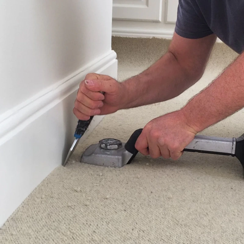 Tucking carpet edges into a baseboard with a bolster.