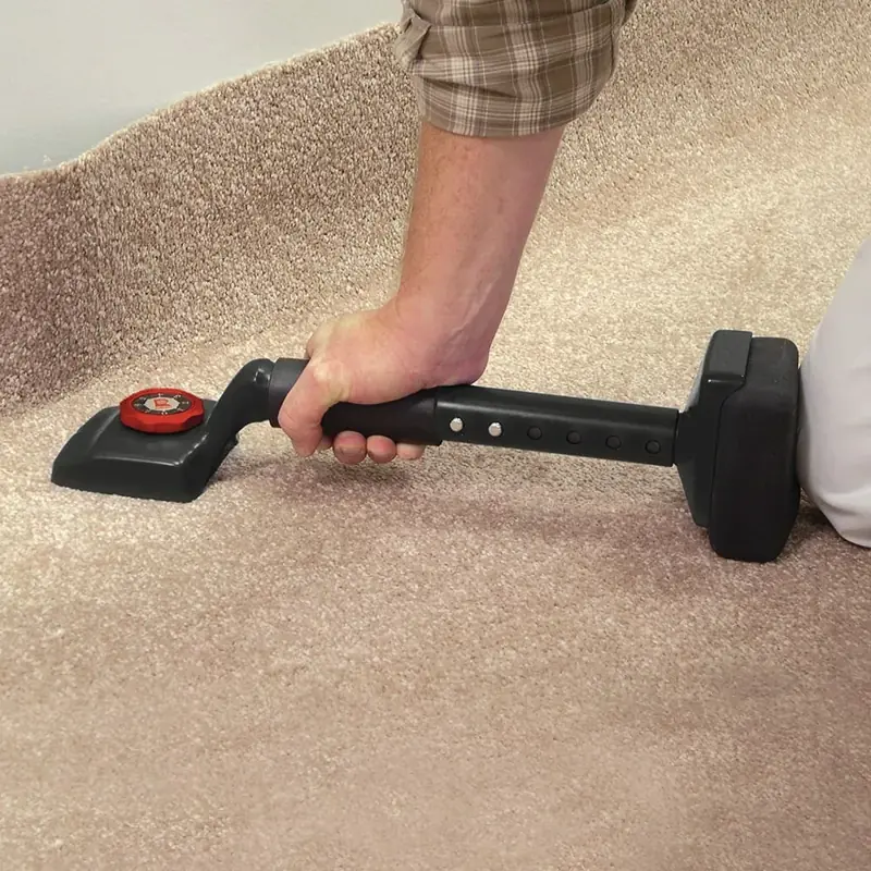 Using a carpet knee kicker to stretch beige carpet