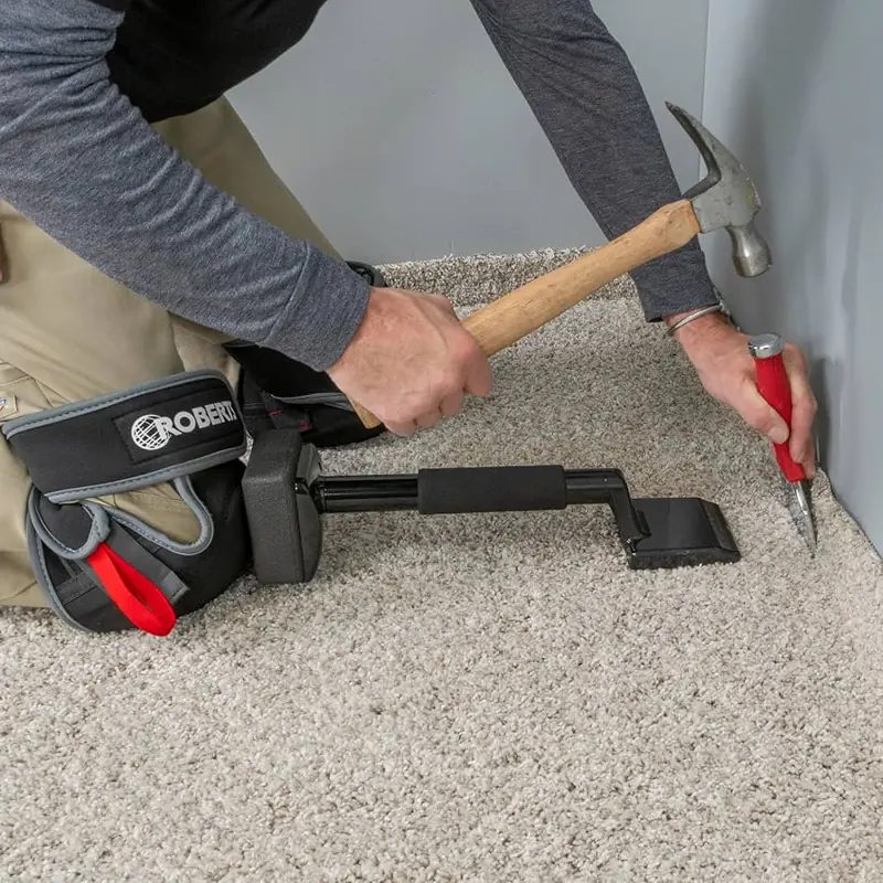 Using a hammer and bolster to secure carpet into a corner